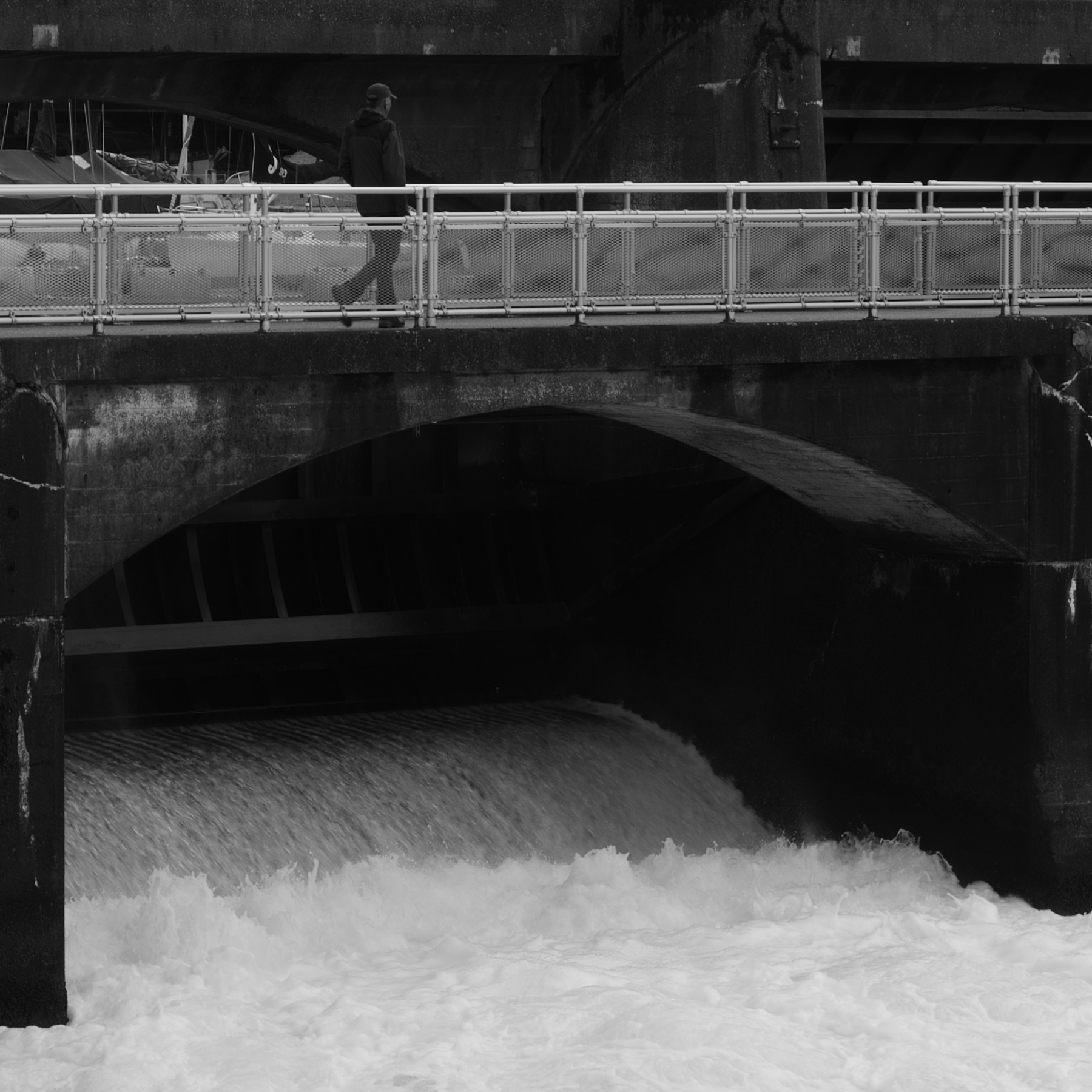 Person walking across a dam, black and white